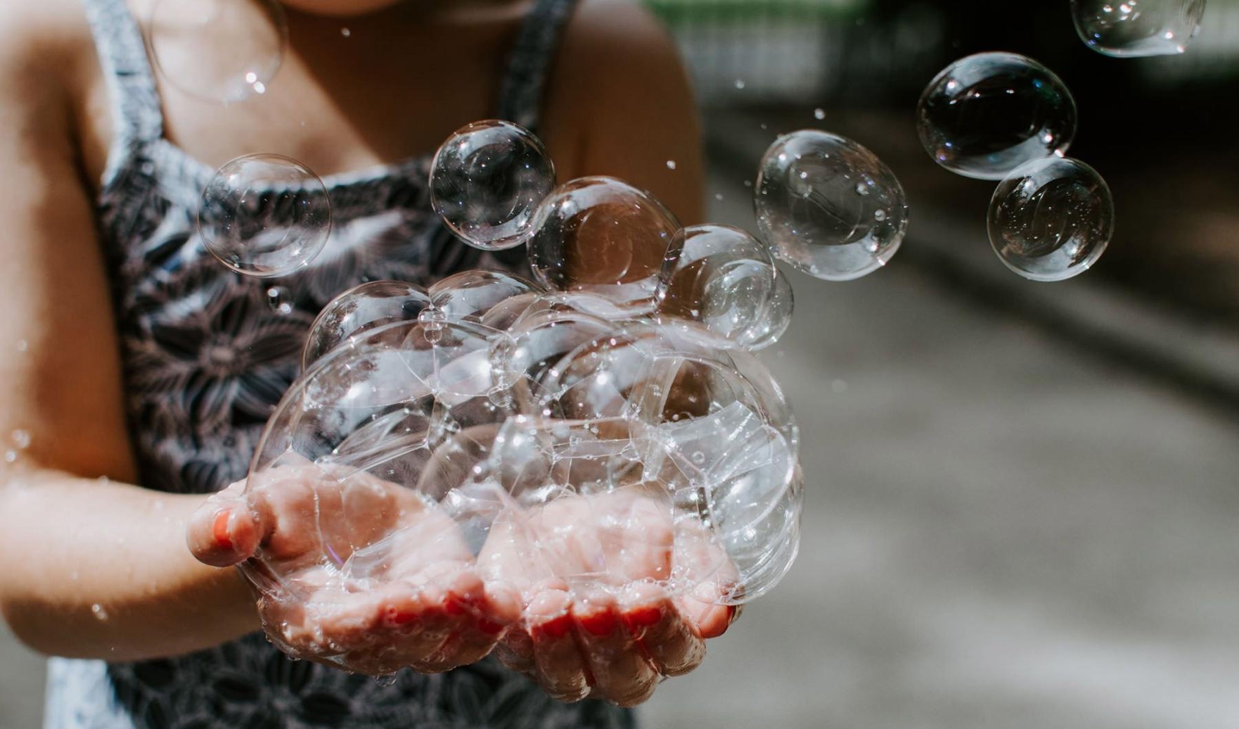 A beautiful community at the heart of all your passions child holding bubbles in her hand as some float away
